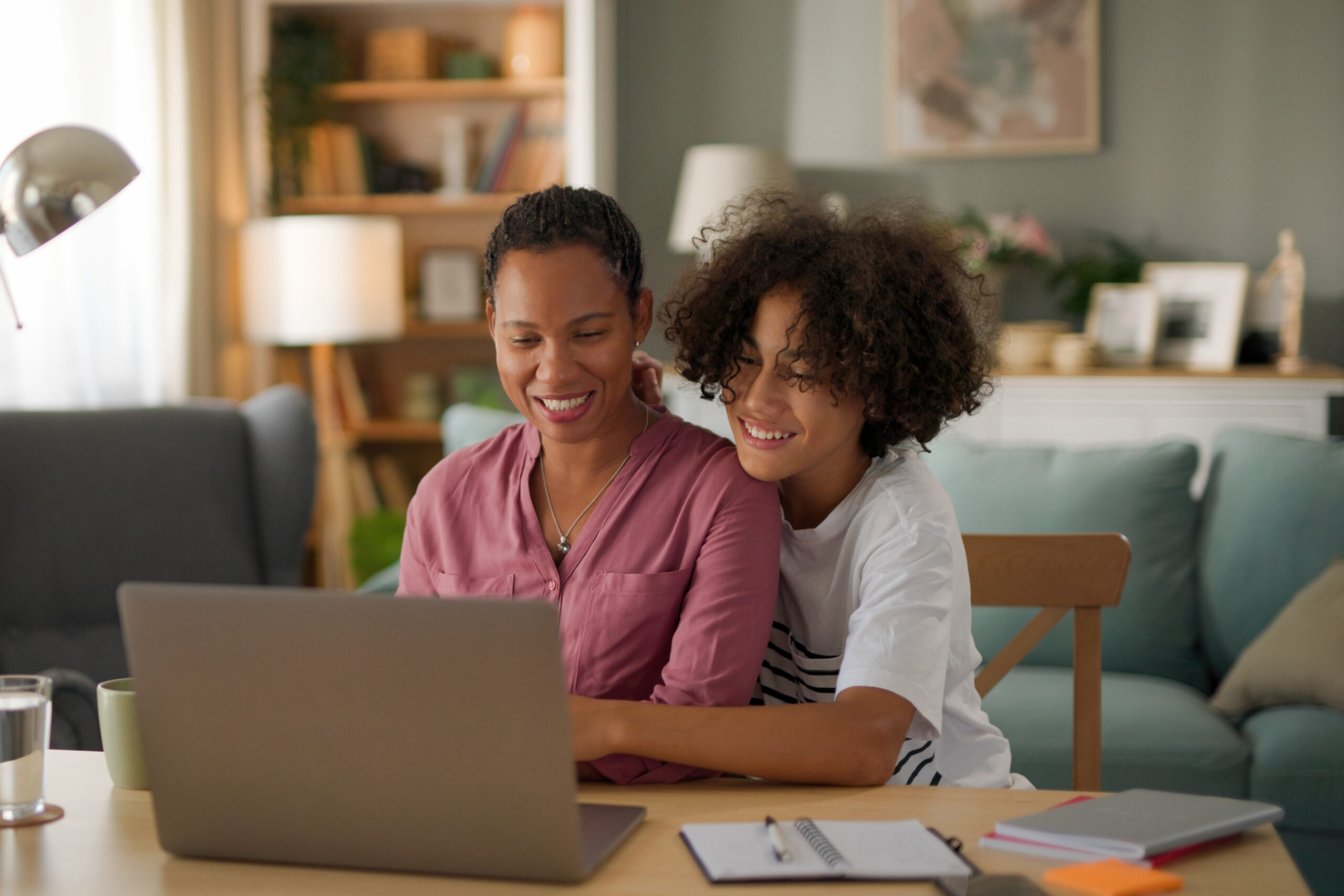 Happy mom and teenage son using a laptop together at home